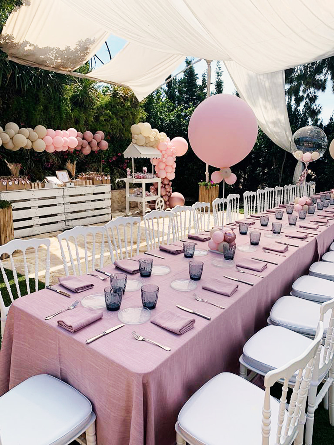 Presentación de mesa para comunión con motivos y decoración en tonos rosa y lila pastel.