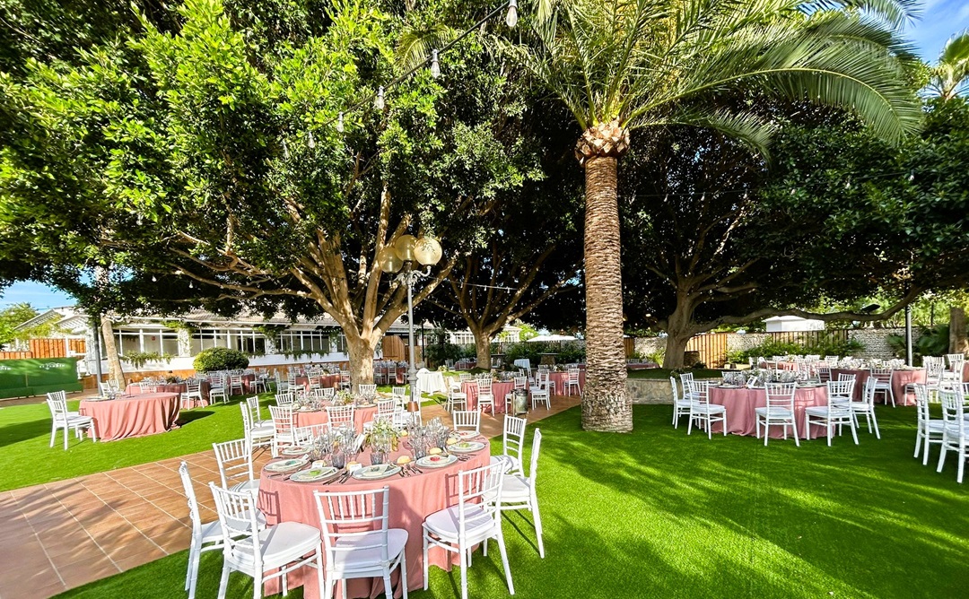 Salón exterior decorado por farolas y palmeras preparado para la celebración de una comunión.